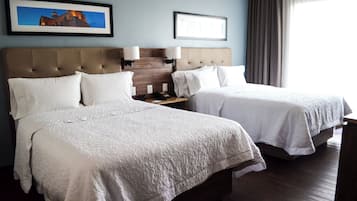Une chambre d’hôtel avec deux lits, une tête de lit, des lampes de chevet, une table de chevet et un tableau encadré au mur.
