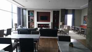 Un moderno vestíbulo de hotel con un sofá de cuero, comedor y un televisor montado en la pared.