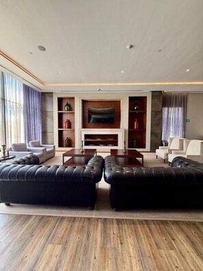 A modern living room with a fireplace, leather sofas, a flat-screen TV, and wooden shelves. - Hampton Inn by Hilton Durango (Durango)