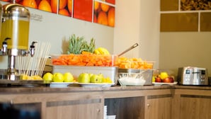 A buffet counter with various fruits and vegetables, a coffee machine, and a toaster.