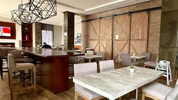 A modern hotel lobby with a bar area, seating arrangements, and a large wooden floor.