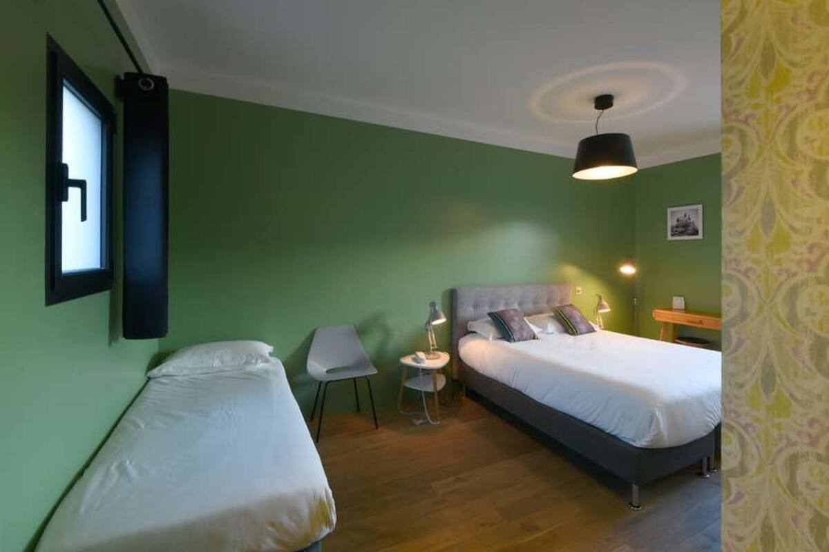 Une chambre avec deux lits, une petite table et une chaise.