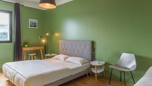 Un dormitorio ordenado con cama, mesitas de noche, una silla y un escritorio.