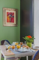 Uma mesa de café da manhã com uma xícara de café, um copo de suco de laranja, croissants e uma cesta de frutas.