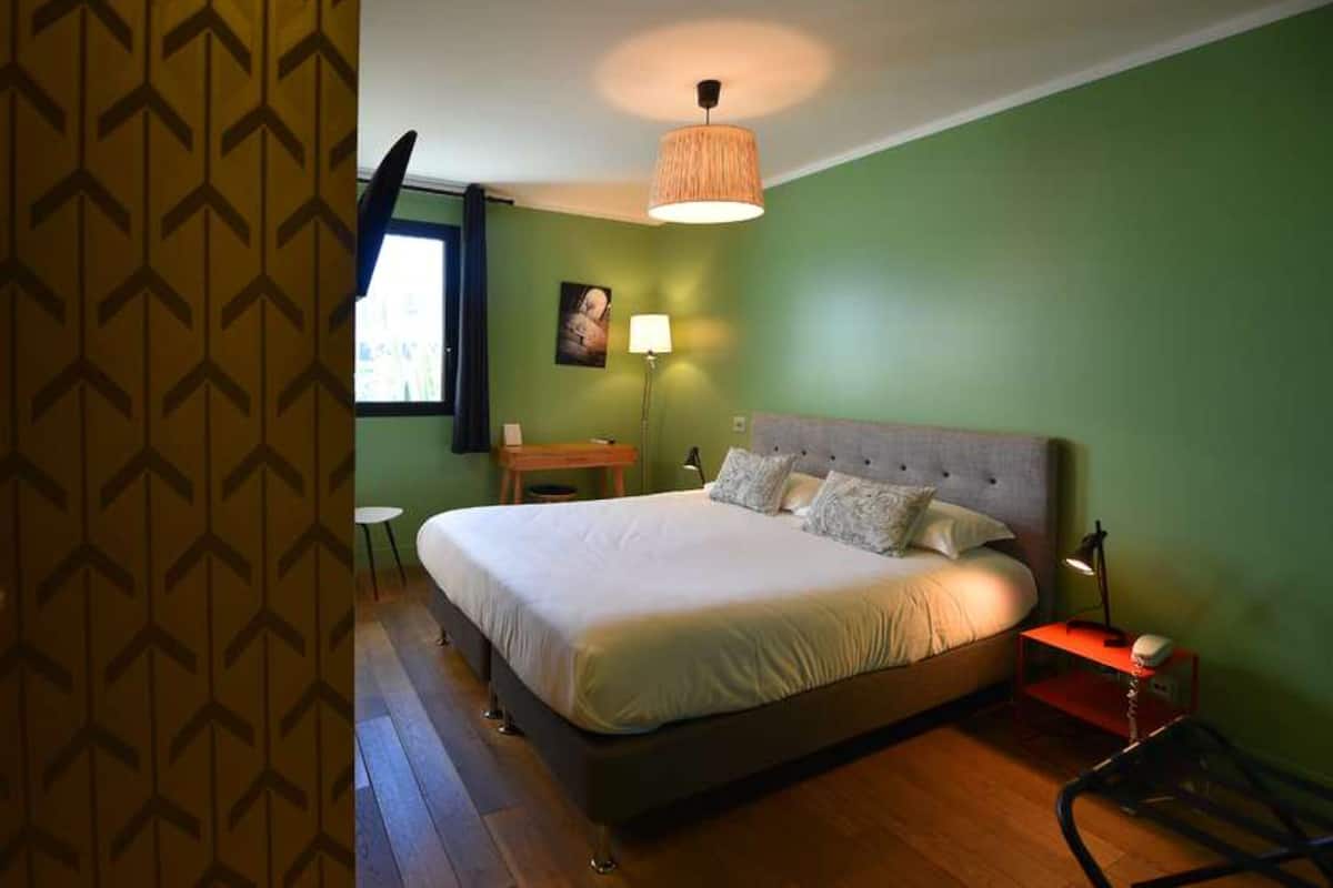 Une chambre à coucher avec un grand lit, une table de chevet, une lampe et une chaise.