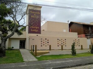A building with a sign for 'Pousada & Bistro Floripa Lodge' and a numbered address '123'. - Floripa Lodge Pousada & Bistrô (Florianópolis)