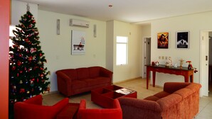 A living room with a Christmas tree, red furniture, and holiday decorations. - Floripa Lodge Pousada & Bistrô (Florianópolis)