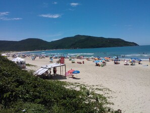 A beach with umbrellas, tents, and people. - Floripa Lodge Pousada & Bistrô (Florianópolis)