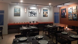 A restaurant with tables set for dining, a long counter with a red tablecloth, and movie posters on the walls. - Floripa Lodge Pousada & Bistrô (Florianópolis)