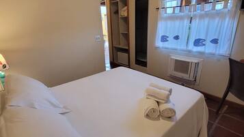 A bedroom with a bed, a wardrobe, a window with curtains, and a radiator.