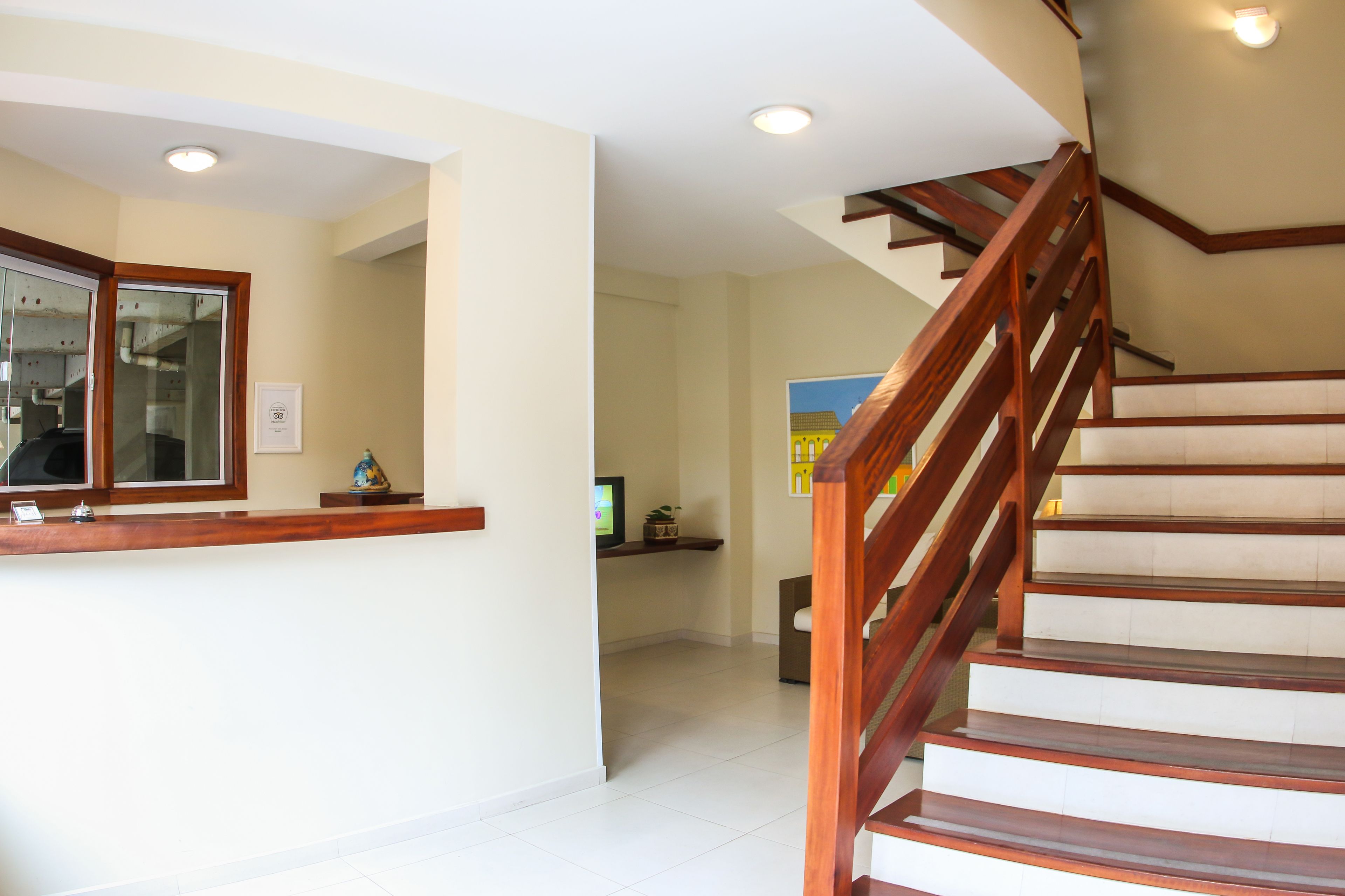 A reception area with a wooden counter, a staircase, and a tiled floor.