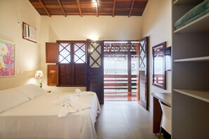 A hotel room with a bed, a nightstand, a lamp, and a view through a wooden door. - Pousada Don Diego (Ubatuba)