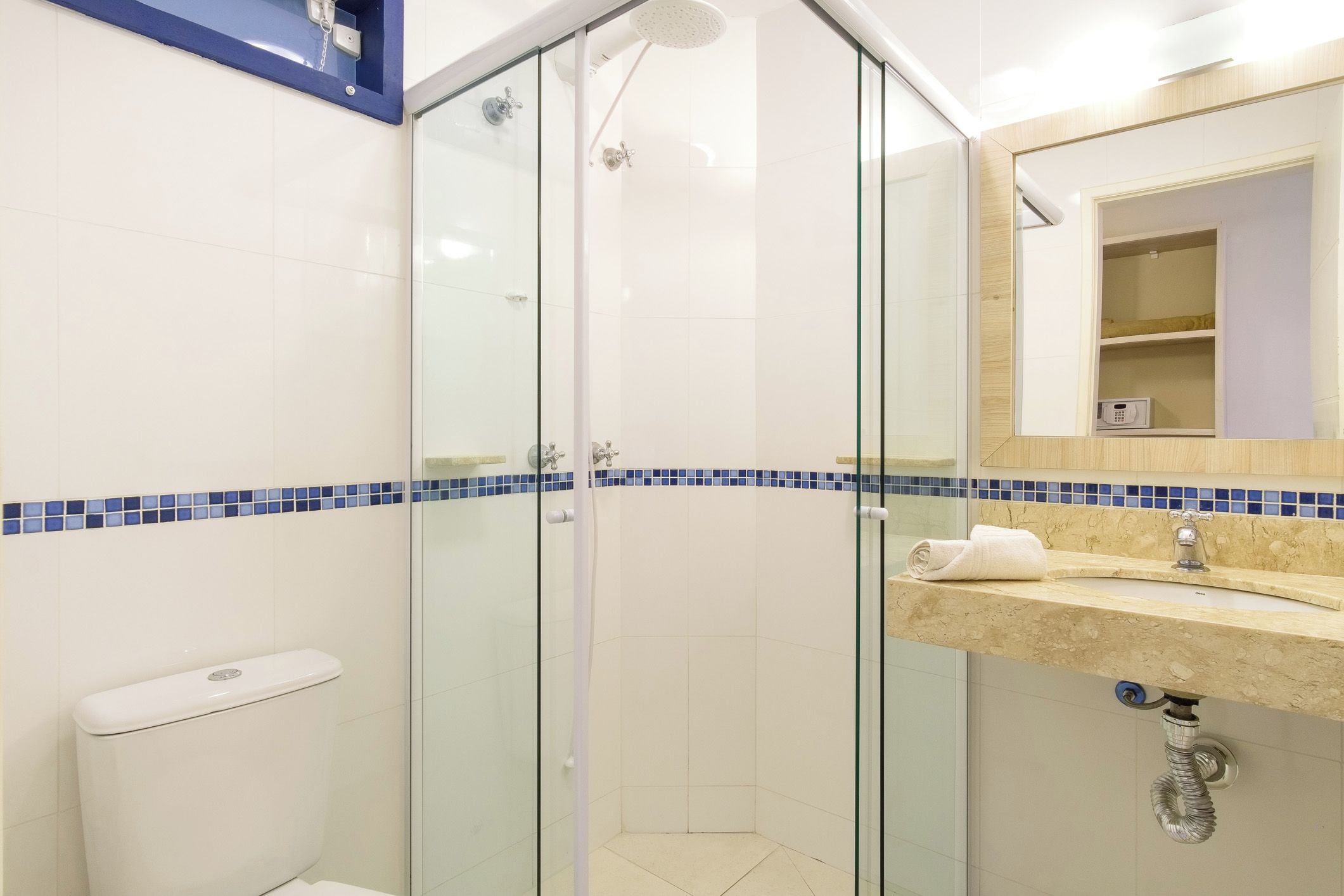 A modern bathroom with a glass-enclosed shower, a toilet, and a sink with a mirror above it.