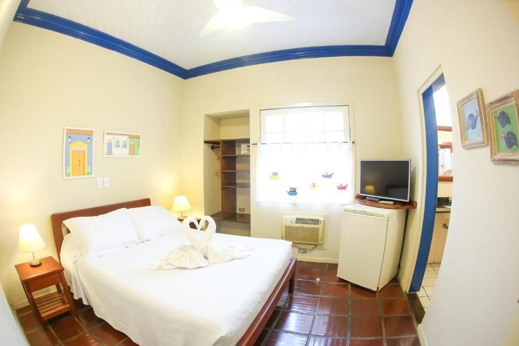 Une chambre d’hôtel avec un lit, des lampes de chevet, une télévision, une fenêtre et une armoire.