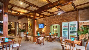 A restaurant with wooden tables and chairs, brick walls, and a television on the wall. - Pousada Don Diego (Ubatuba)