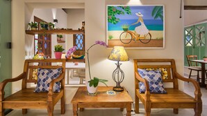A cozy living area with two wooden sofas, a small table, and a wall-mounted lamp. - Pousada Don Diego (Ubatuba)