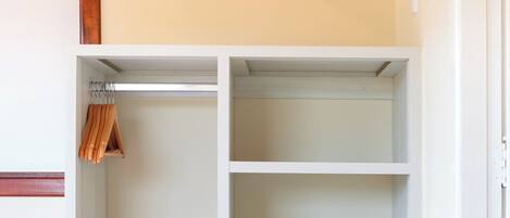 Una habitación con una cama, un armario blanco y un pequeño electrodoméstico, posiblemente un minibar.