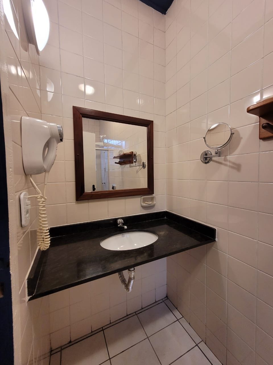 A bathroom with a white sink, a mirror, a hairdryer, and a towel rack.