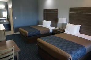 Ett hotellrum med två sängar, ett skrivbord och en stol.