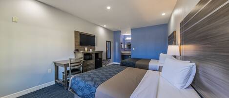 Habitación de hotel con cama, escritorio, silla, espejo y lámpara.