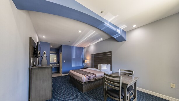 A hotel room with a bed, desk, chair, and a small kitchenette area. - Home Place Inn Spring I-45 North & 1960 (Houston)