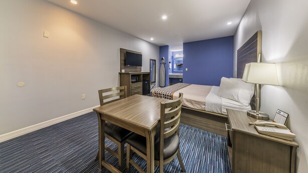 A hotel room with a bed, a desk, a chair, a TV, and a lamp. - Home Place Inn Spring I-45 North & 1960 (Houston)