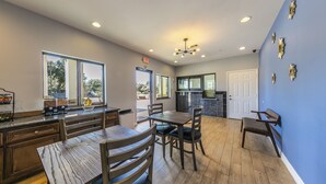 A modern kitchen with wooden cabinetry, a dining area with a table and chairs, and a blue accent wall. - Home Place Inn Spring I-45 North & 1960 (Houston)