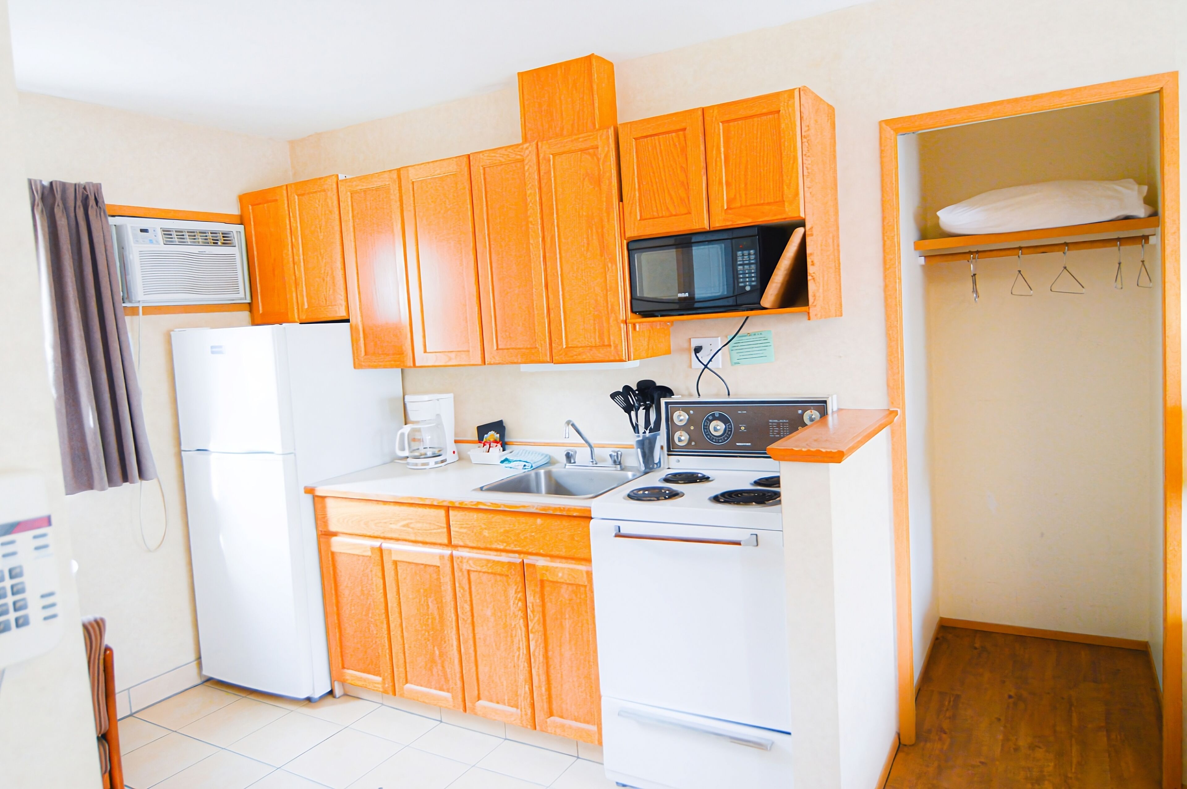 A compact kitchen with wooden cabinets, a microwave, a refrigerator, and a stove.