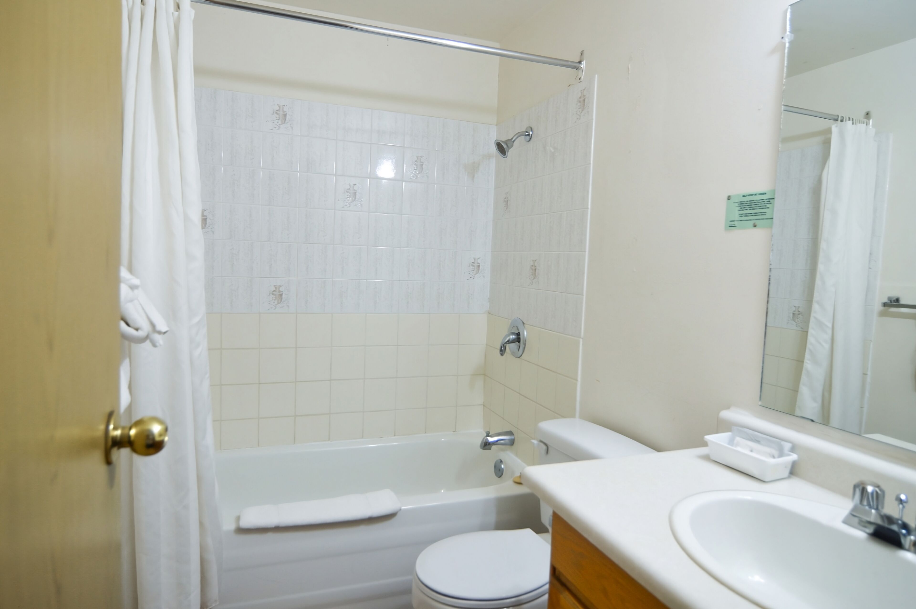 A bathroom with a bathtub, toilet, sink, and a mirror.