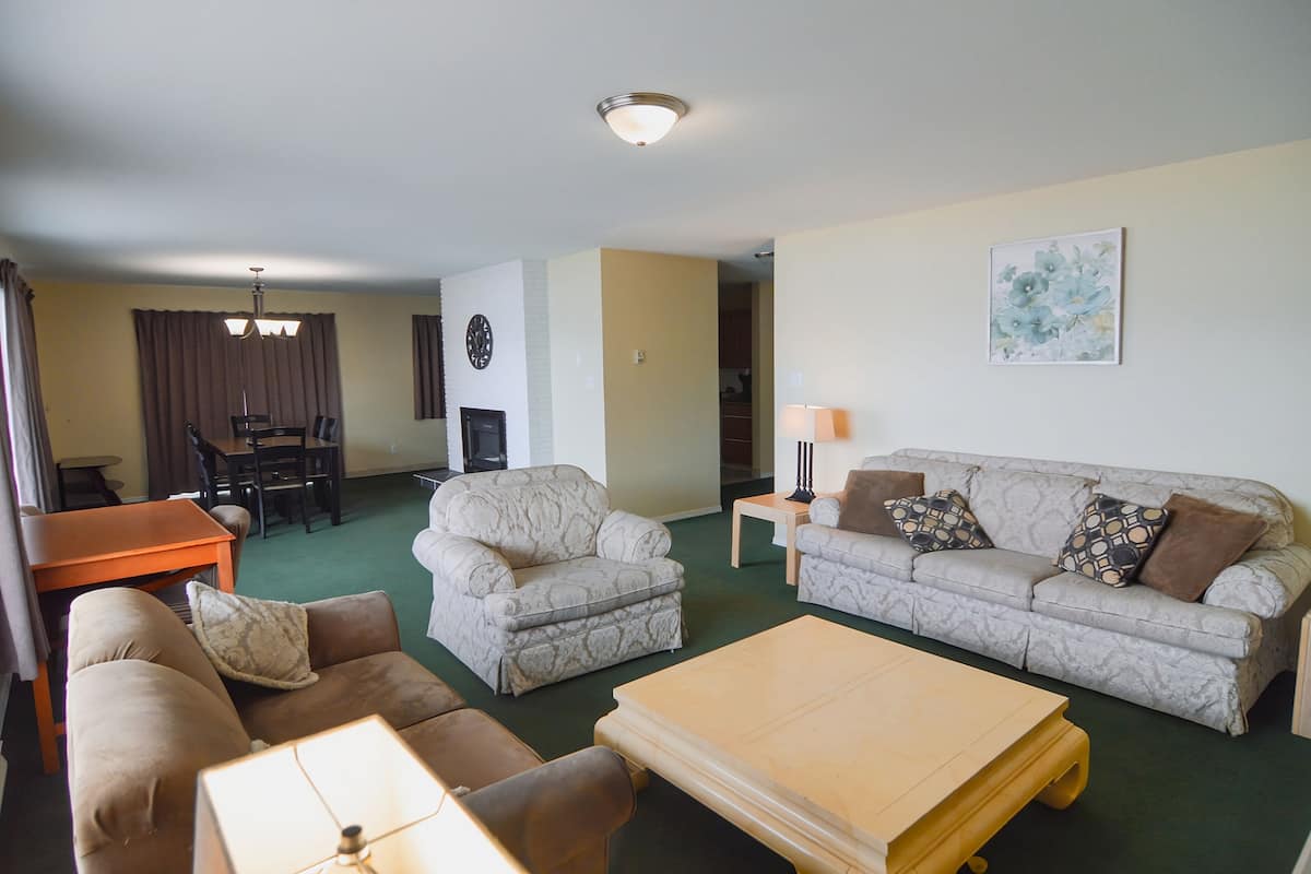 A living room with a sofa, armchair, coffee table, and a dining area with a table and chairs.