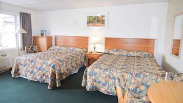 Een hotelkamer met twee bedden, een houten hoofdbord, een nachtkastje met een lamp, een raam met gordijnen en een schilderij aan de muur.
