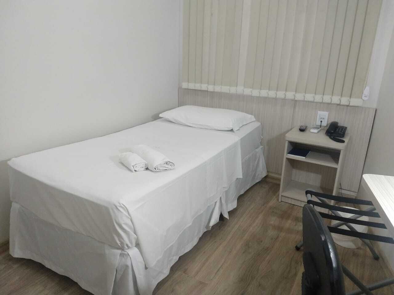 Una habitación pequeña y limpia con dos camas individuales, un escritorio y una silla.