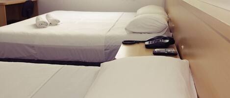 Habitación de hotel con dos camas, un escritorio y un teléfono.
