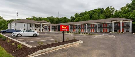 A motel with a central building and two wings, a parking lot, and a sign indicating the name 'Econo Lodge'.