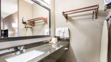 Un baño con un espejo grande, un lavabo y barras para toallas.