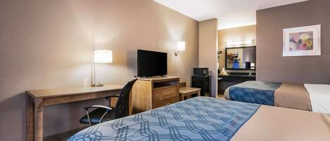 A hotel room with two beds, a desk, a television, and a mirror.