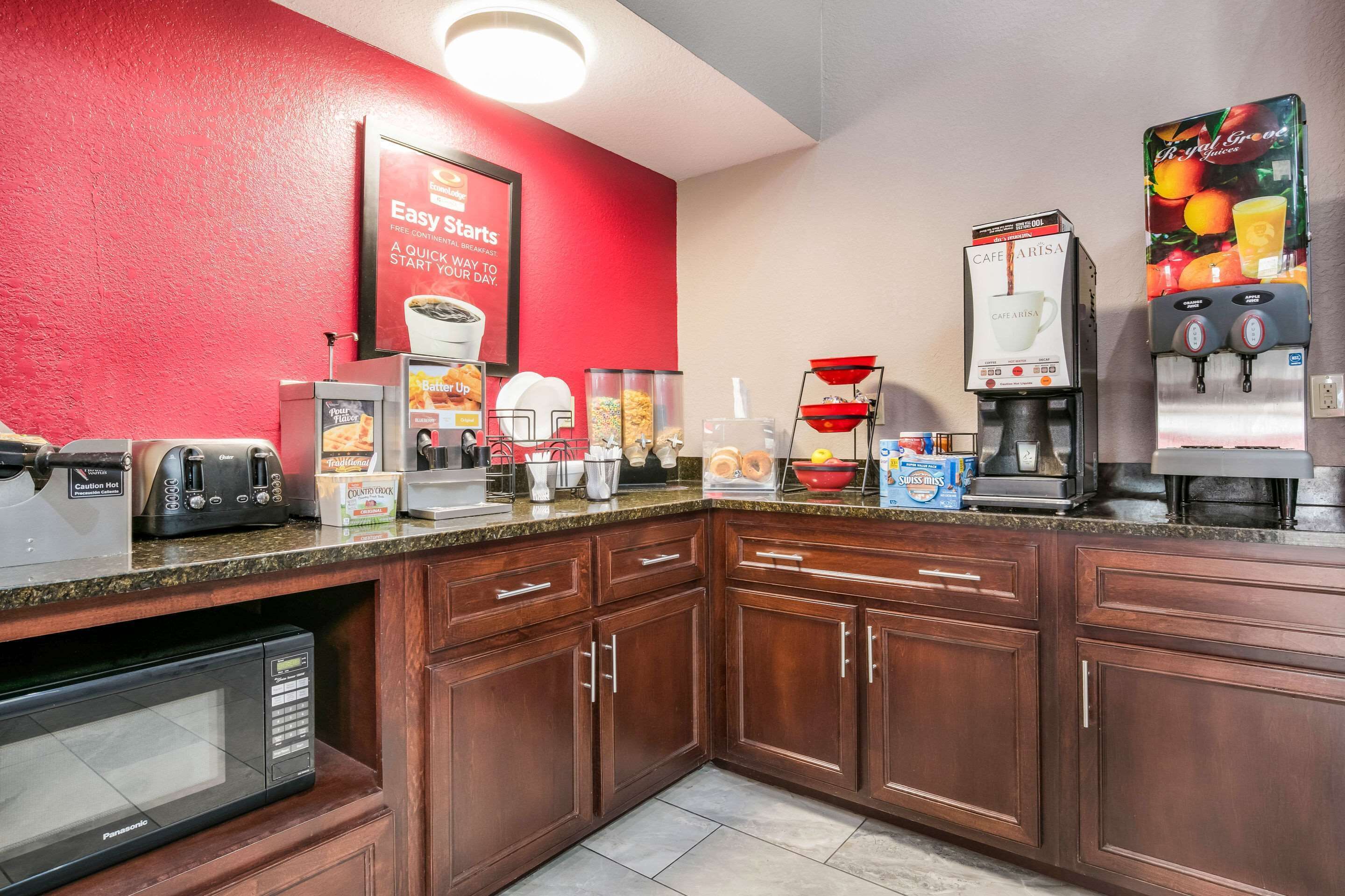 A kitchen area with a red wall, a coffee machine, a toaster, and a microwave.