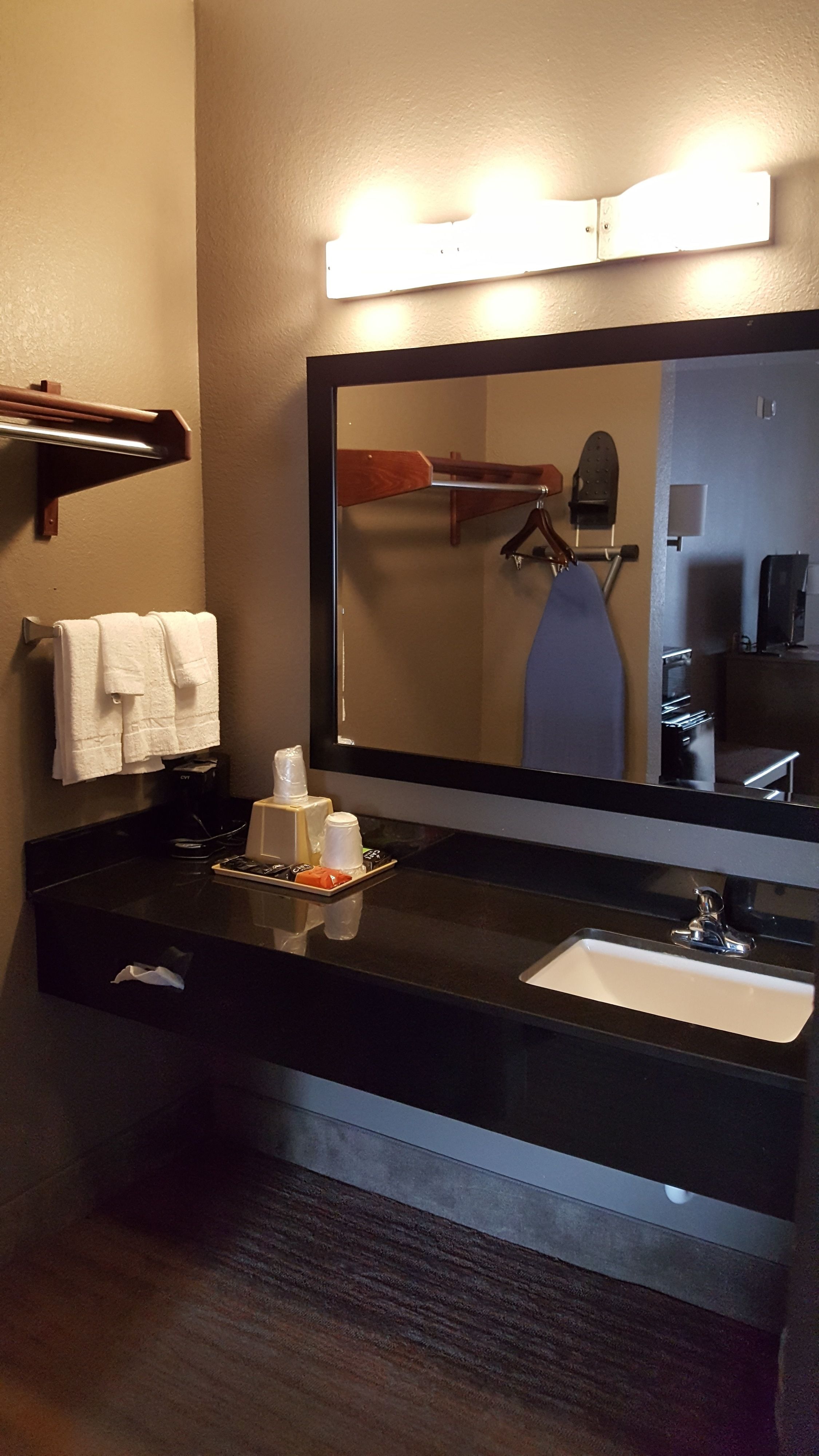 A bathroom with a black sink, a mirror, and a towel rack.