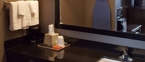 Un baño con un lavabo negro, un espejo y un perchero para toallas.