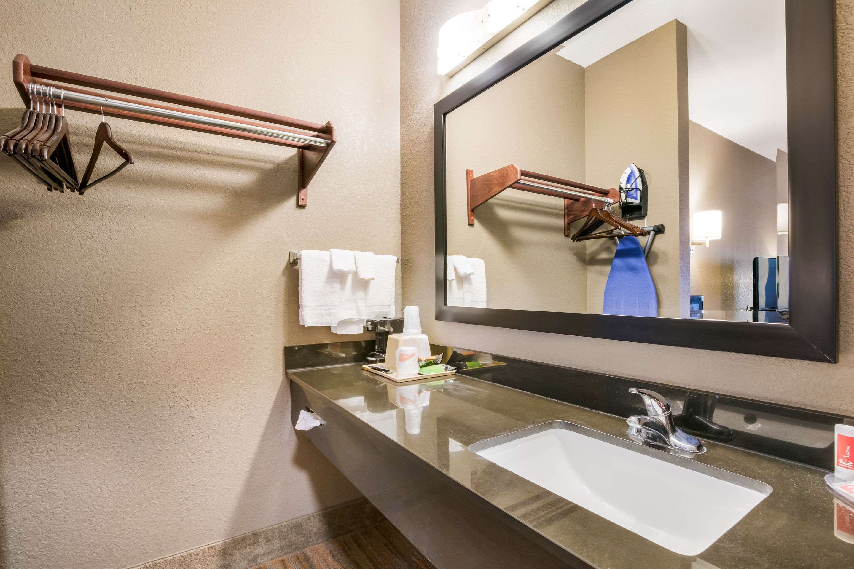 A bathroom with a large mirror, a sink, and towel racks.