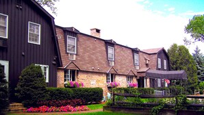Uma casa grande, de dois andares, com fachada de pedra e várias janelas.