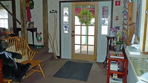 Um quarto aconchegante com uma cadeira de madeira, uma porta adornada com uma grinalda e uma estante com livros e um vaso.