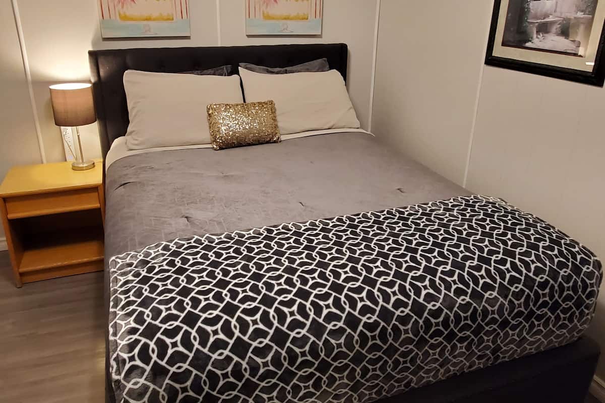 A neatly arranged bedroom with a bed, bedside tables, and wall art.