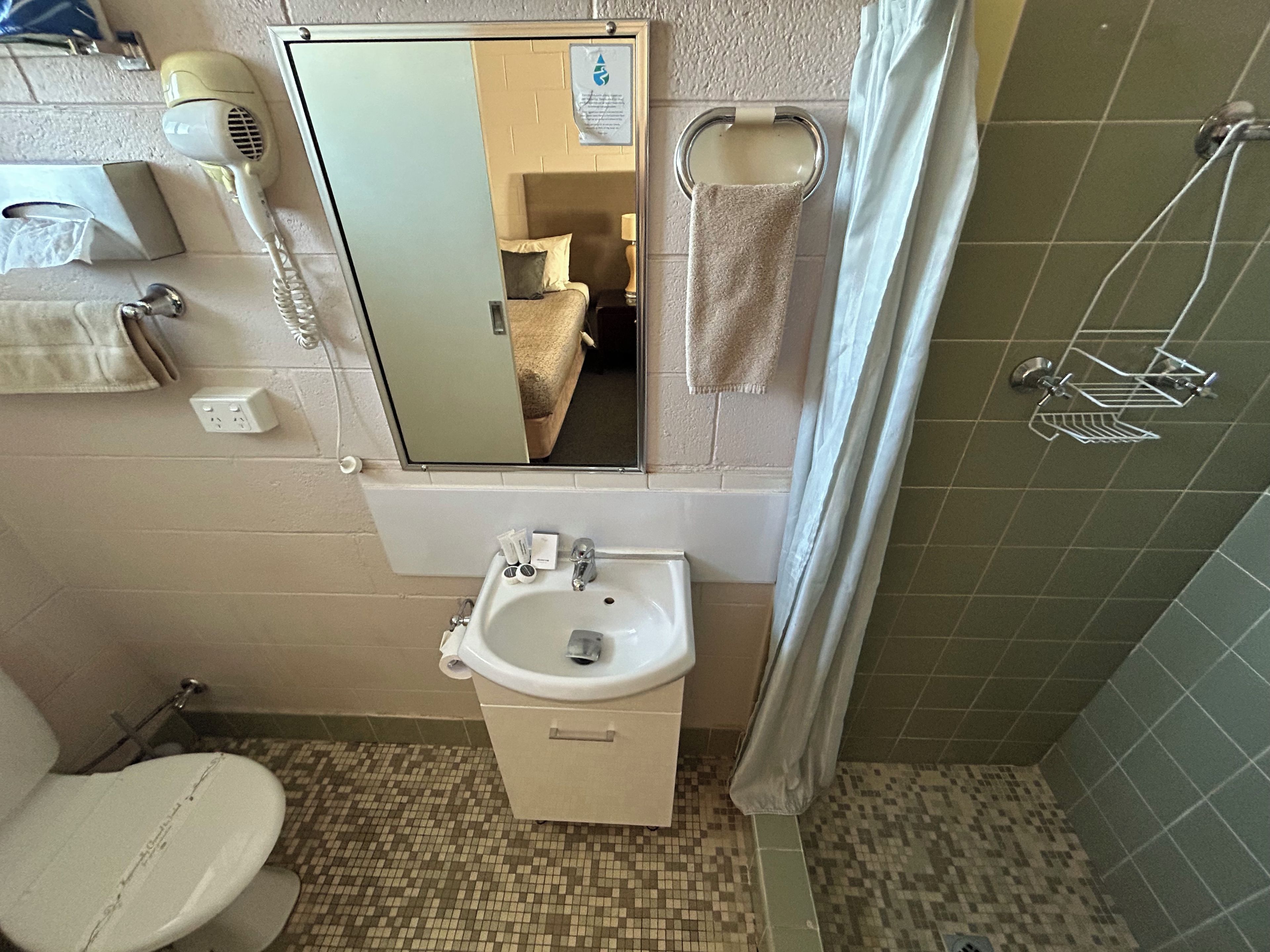 A bathroom with a toilet, sink, and shower area.