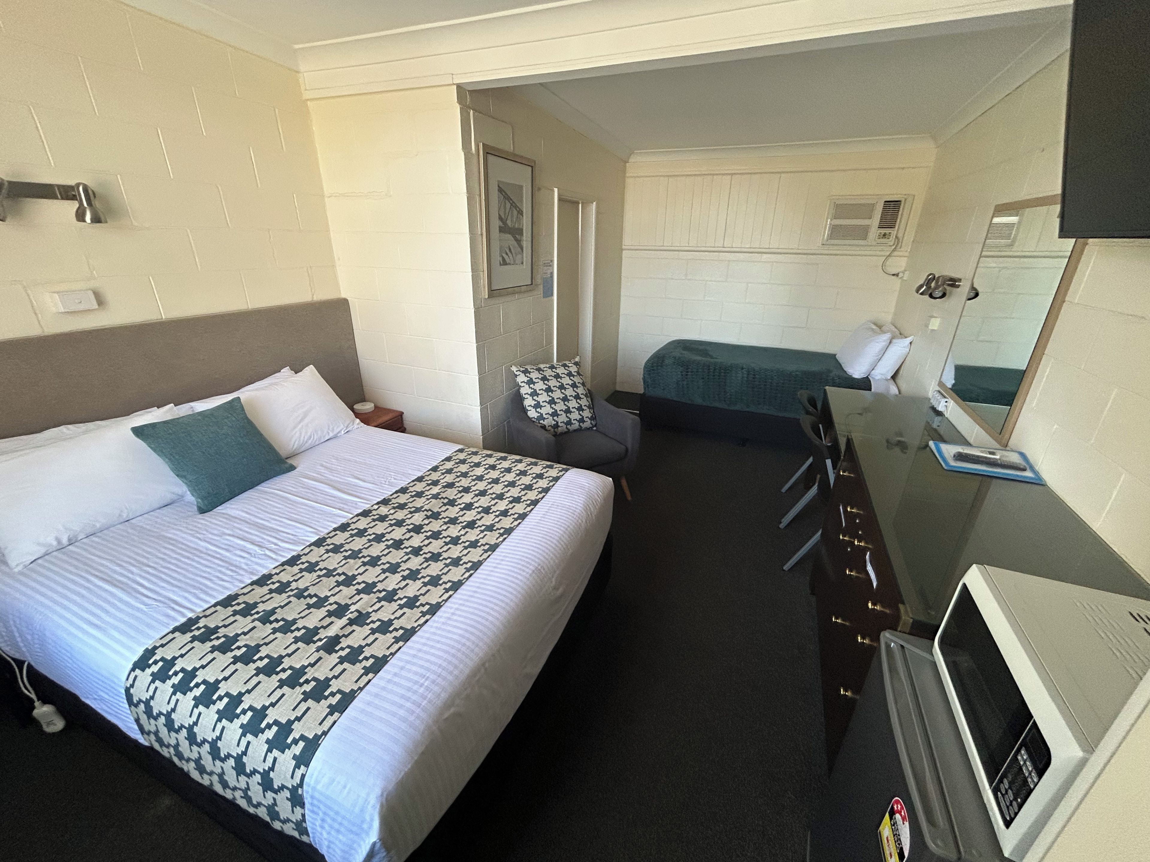 A hotel room with a large bed, a smaller bed, a desk with a computer, and a TV.