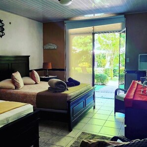 A bedroom with a bed, bedside table, lamp, and a view of greenery through a glass door. - Hotel Belvedere (Sámara)