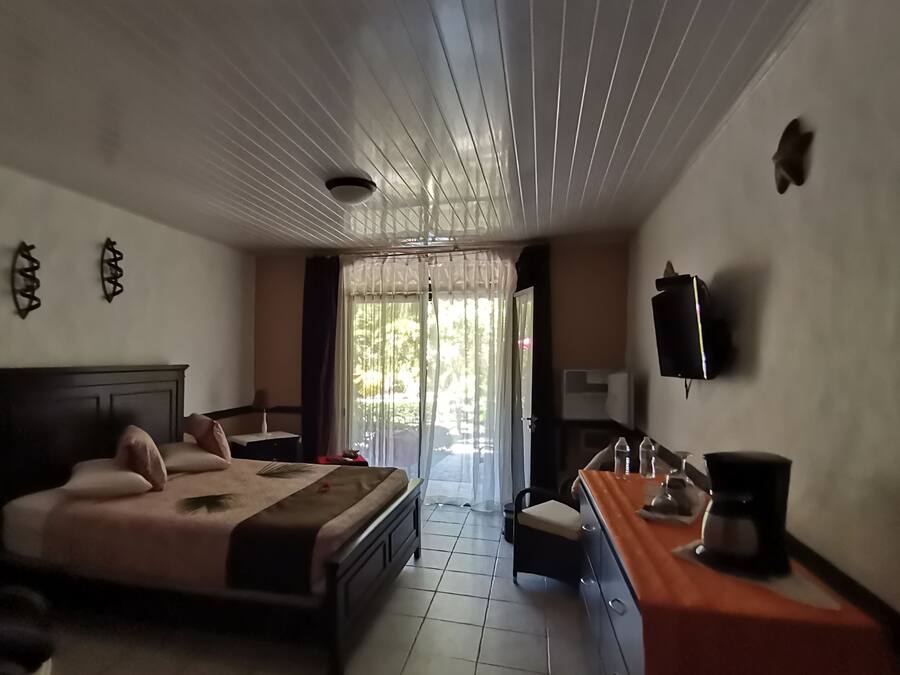 A hotel room with a bed, a desk, a chair, a TV, and a window with curtains.