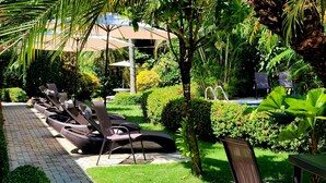 A garden with a pool, lounge chairs, and a fountain. - Hotel Belvedere (Sámara)