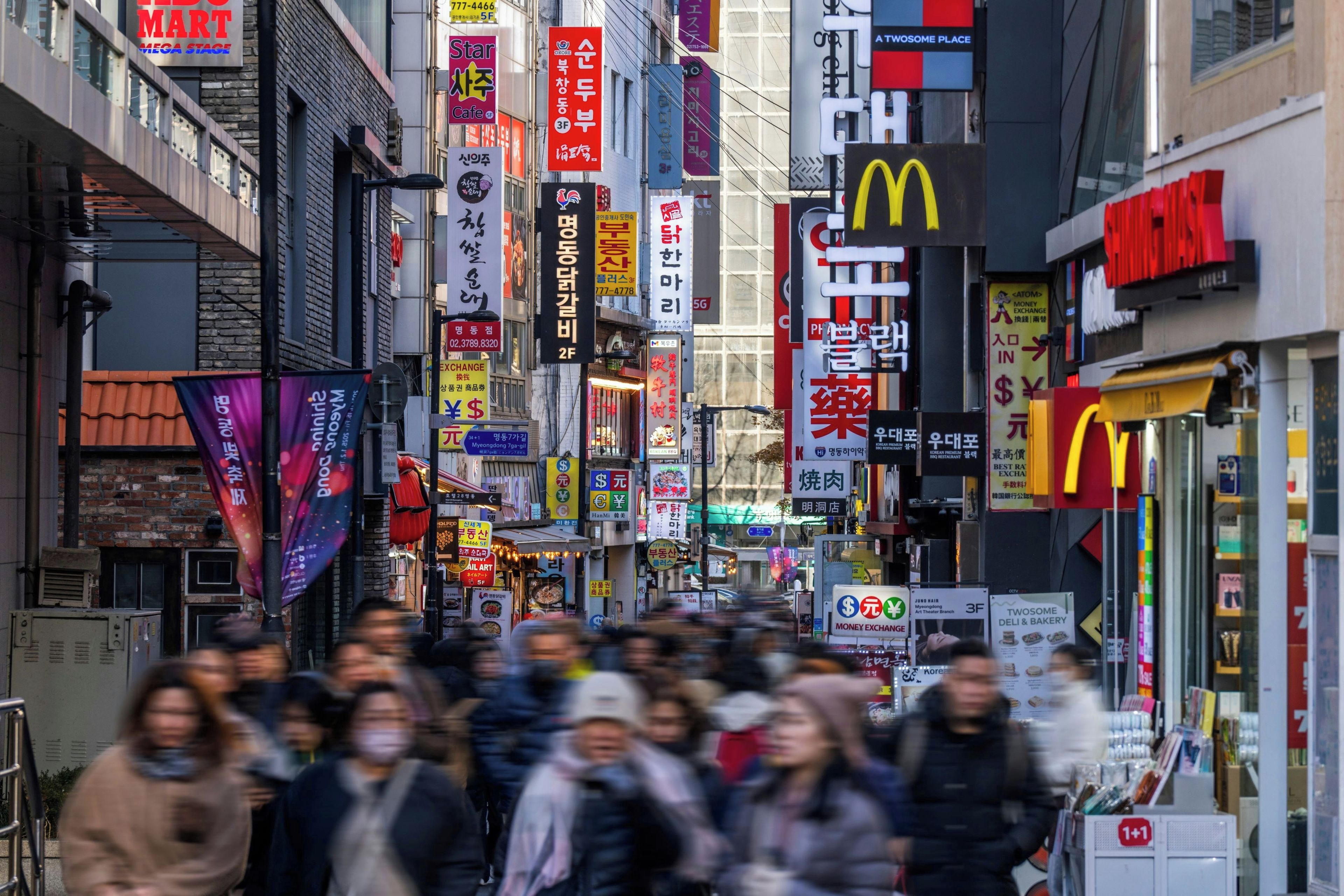 A busy urban street with various commercial signs and storefronts.