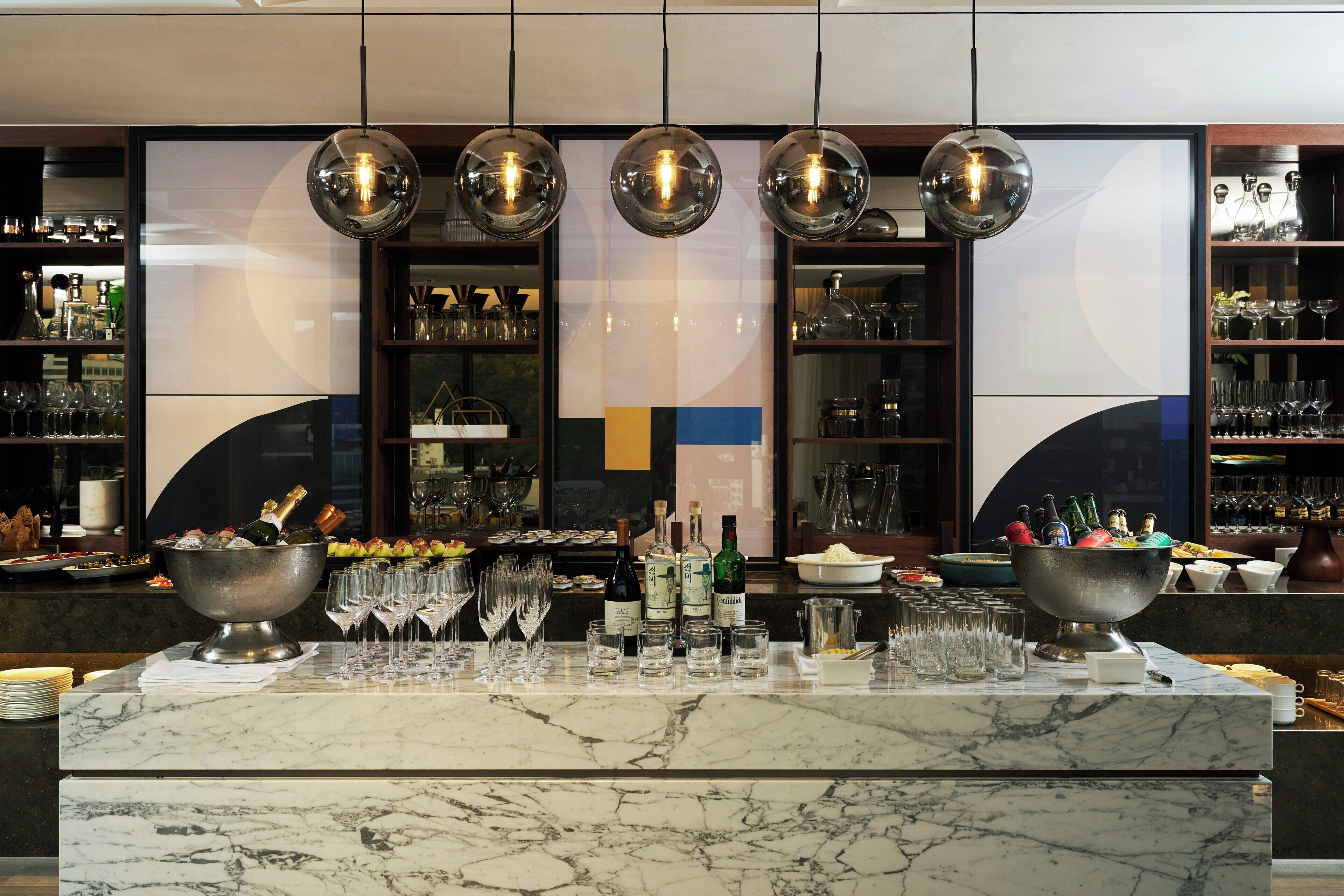 A bar area with a marble countertop, bottles of alcohol, and glasses.